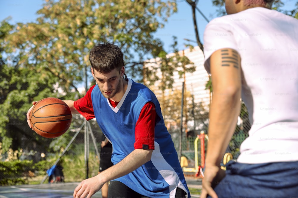 Un joven sosteniendo una pelota de baloncesto mientras está de pie junto a otro joven