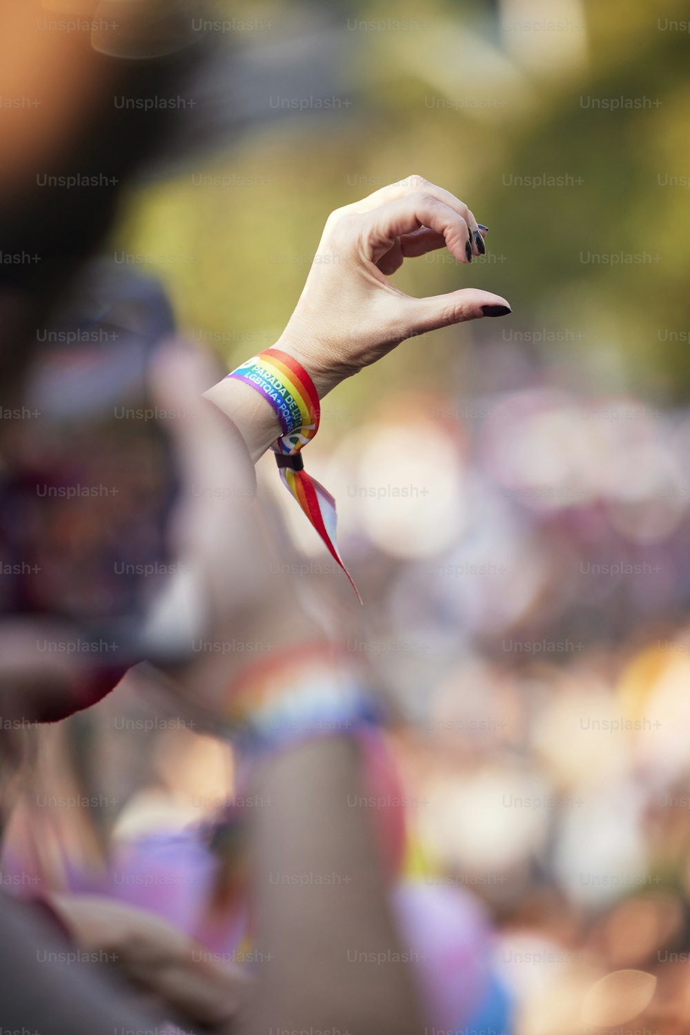 Une main de femme tenant un bracelet arc-en-ciel