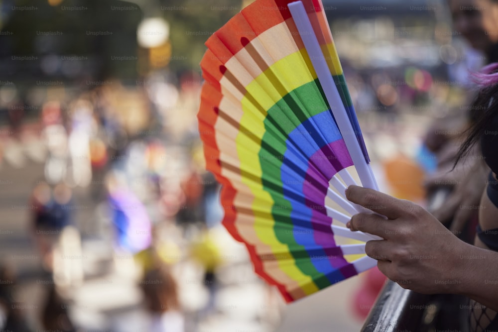 Una mujer sosteniendo un abanico de colores del arco iris en su mano