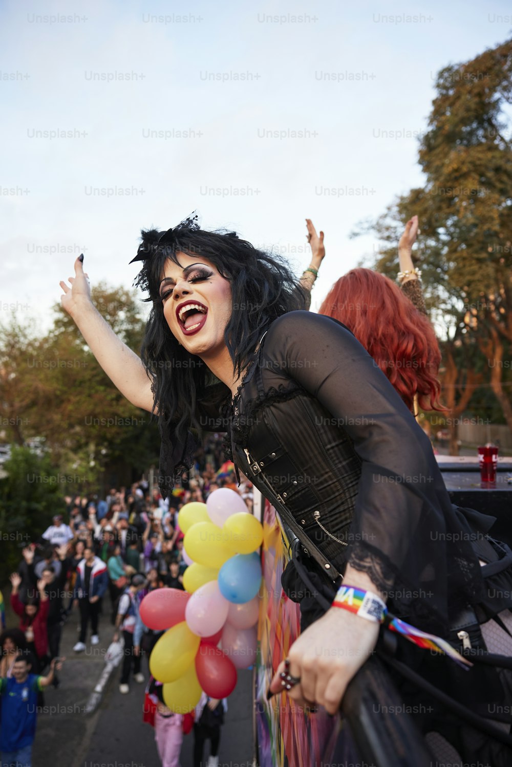 a woman with black hair and makeup holding a bunch of balloons