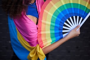 uma mulher segurando um ventilador colorido em suas mãos