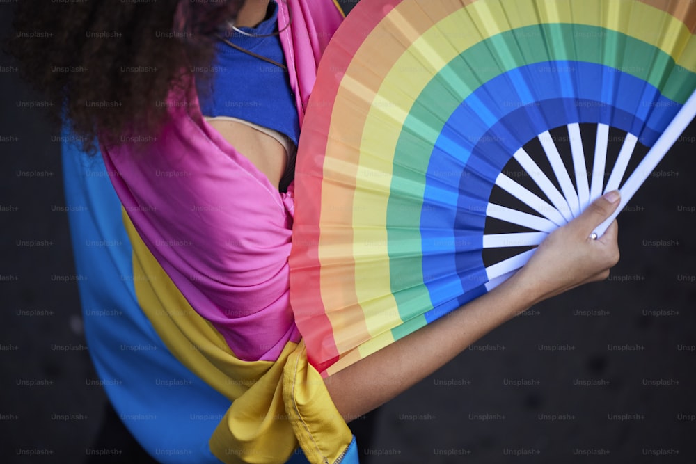 uma mulher segurando um ventilador colorido em suas mãos