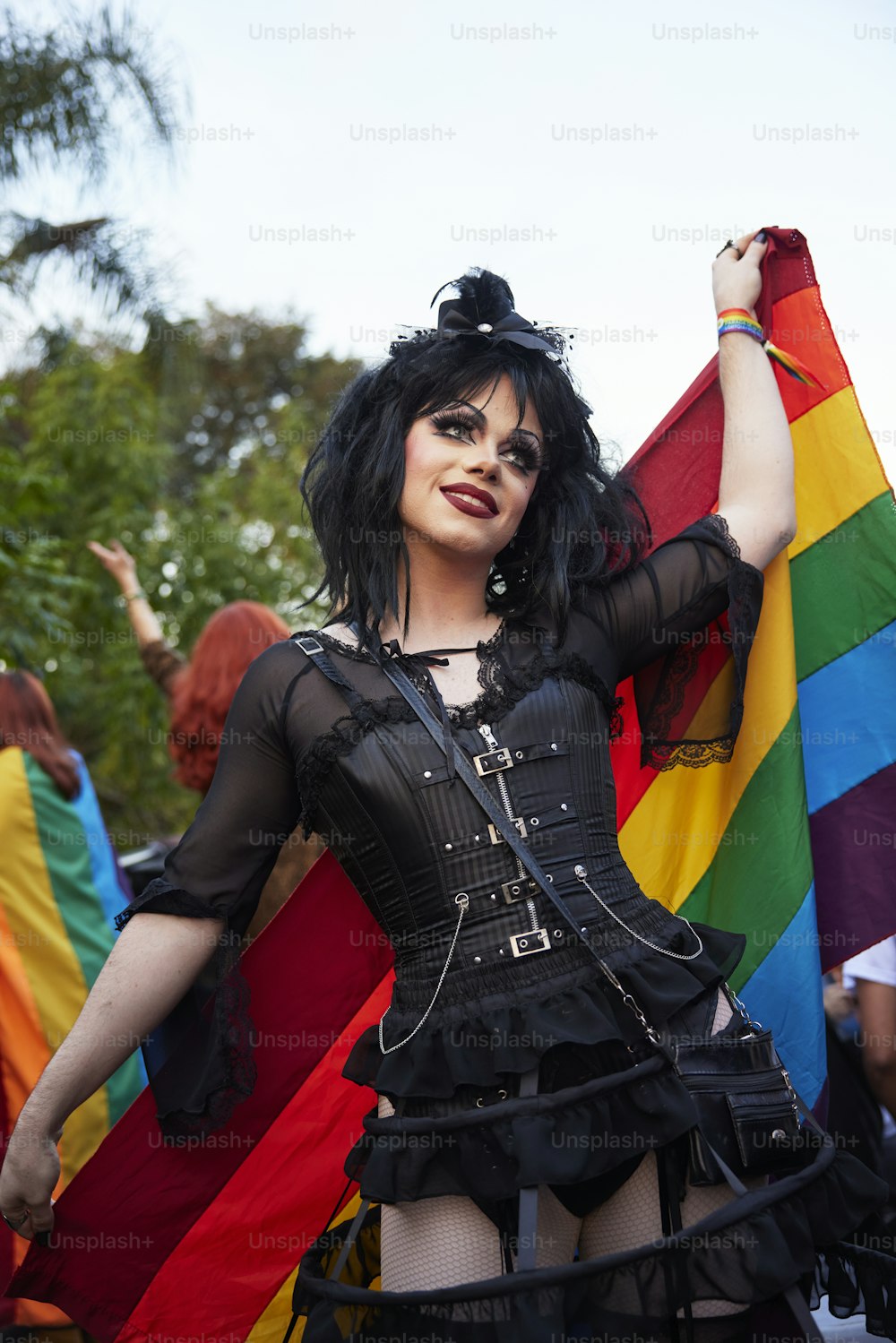 Una mujer con un corsé sosteniendo una bandera del arco iris