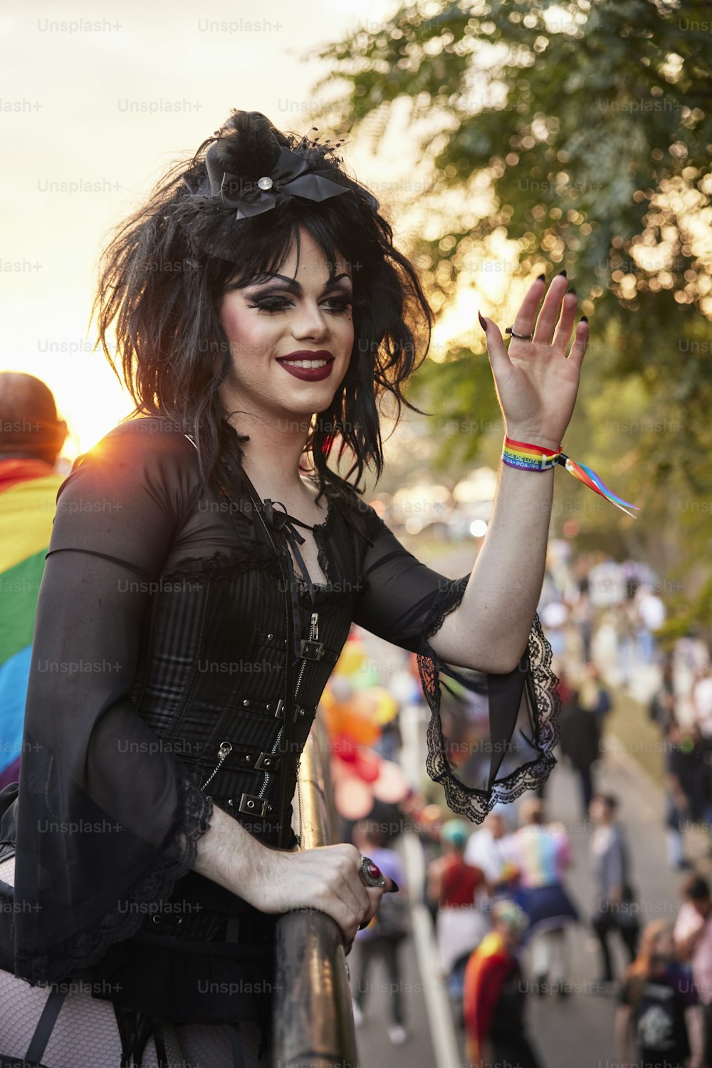 Una mujer con cabello oscuro y maquillaje sosteniendo una bandera del arco iris