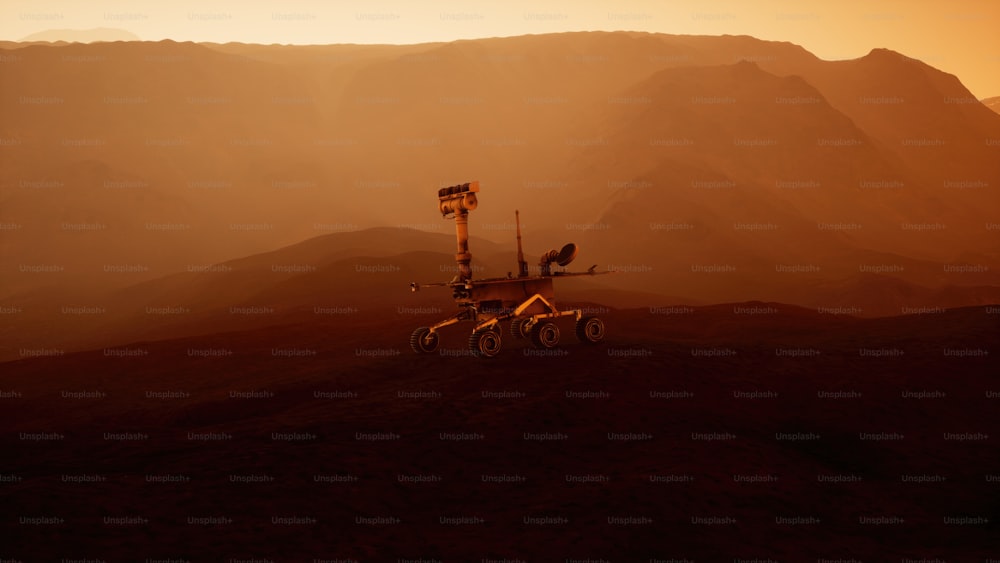 a large vehicle on a dirt field with mountains in the background