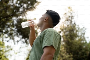 Un hombre bebiendo agua de una botella de plástico
