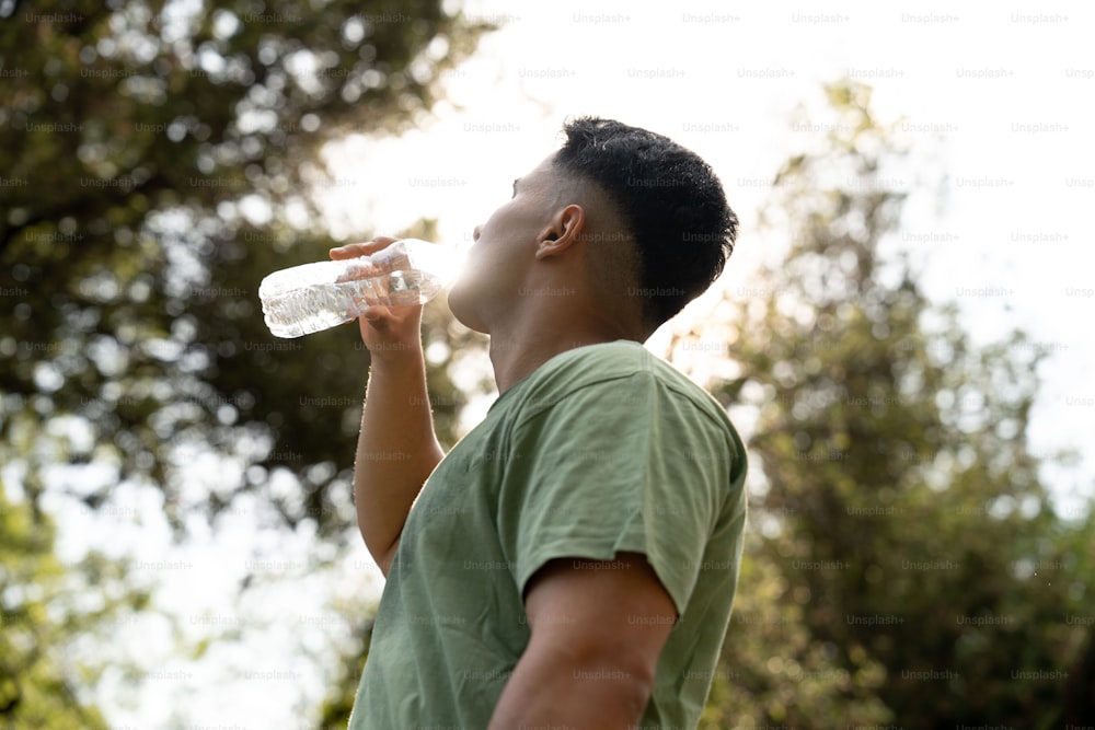um homem bebendo água de uma garrafa de plástico