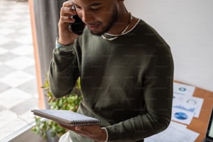 Un homme parlant sur un téléphone cellulaire tout en tenant un presse-papiers