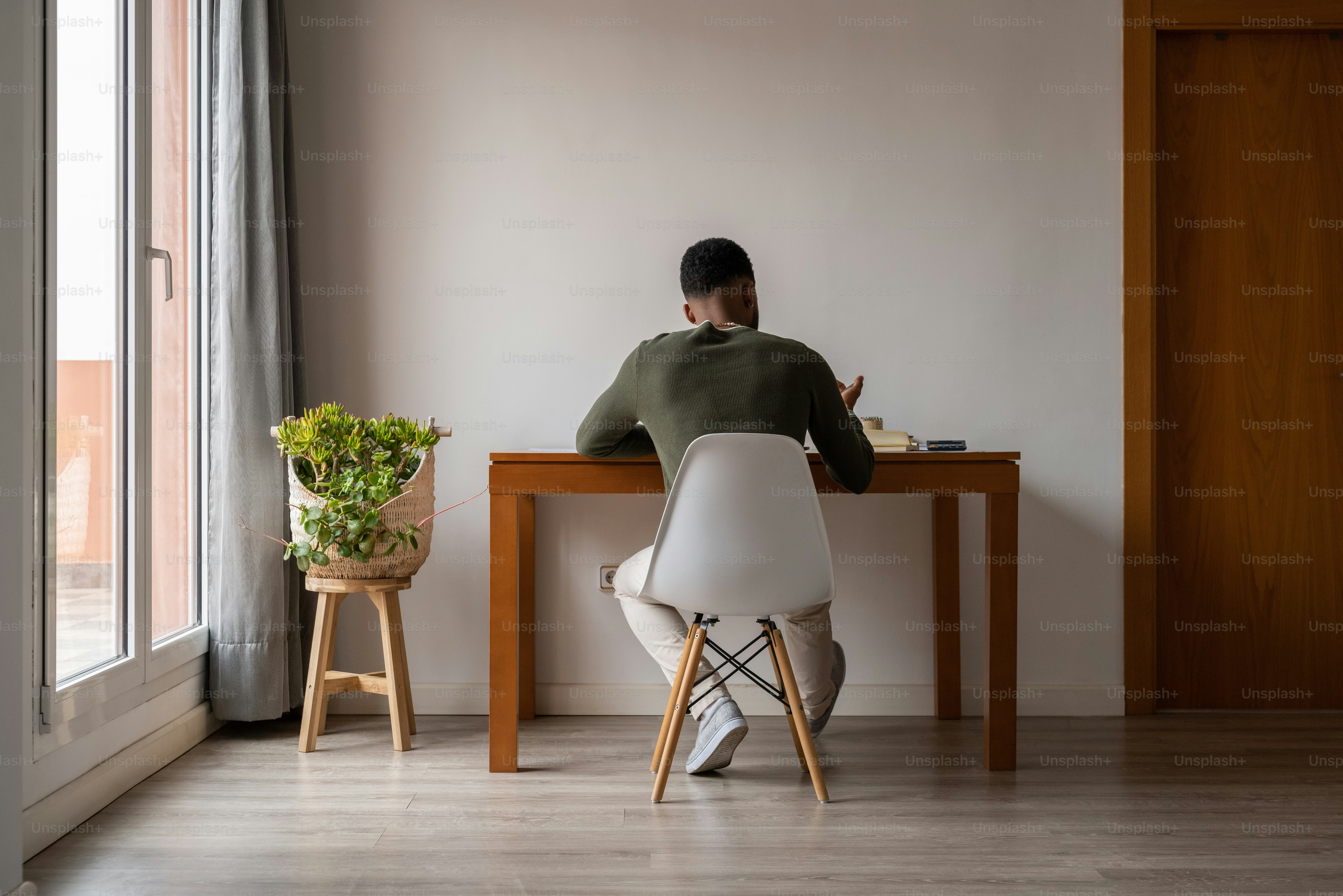 Un hombre sentado en una mesa con una planta frente a él