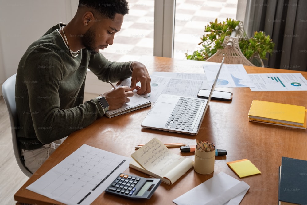 a man sitting at a table with a laptop and calculator