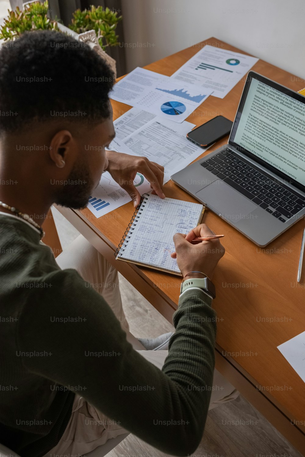 Un hombre sentado en un escritorio escribiendo en un bloc de notas