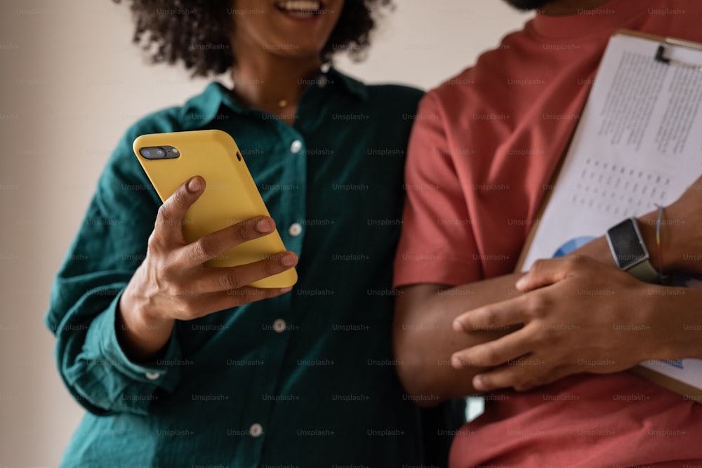 duas pessoas em pé uma ao lado da outra olhando para um celular