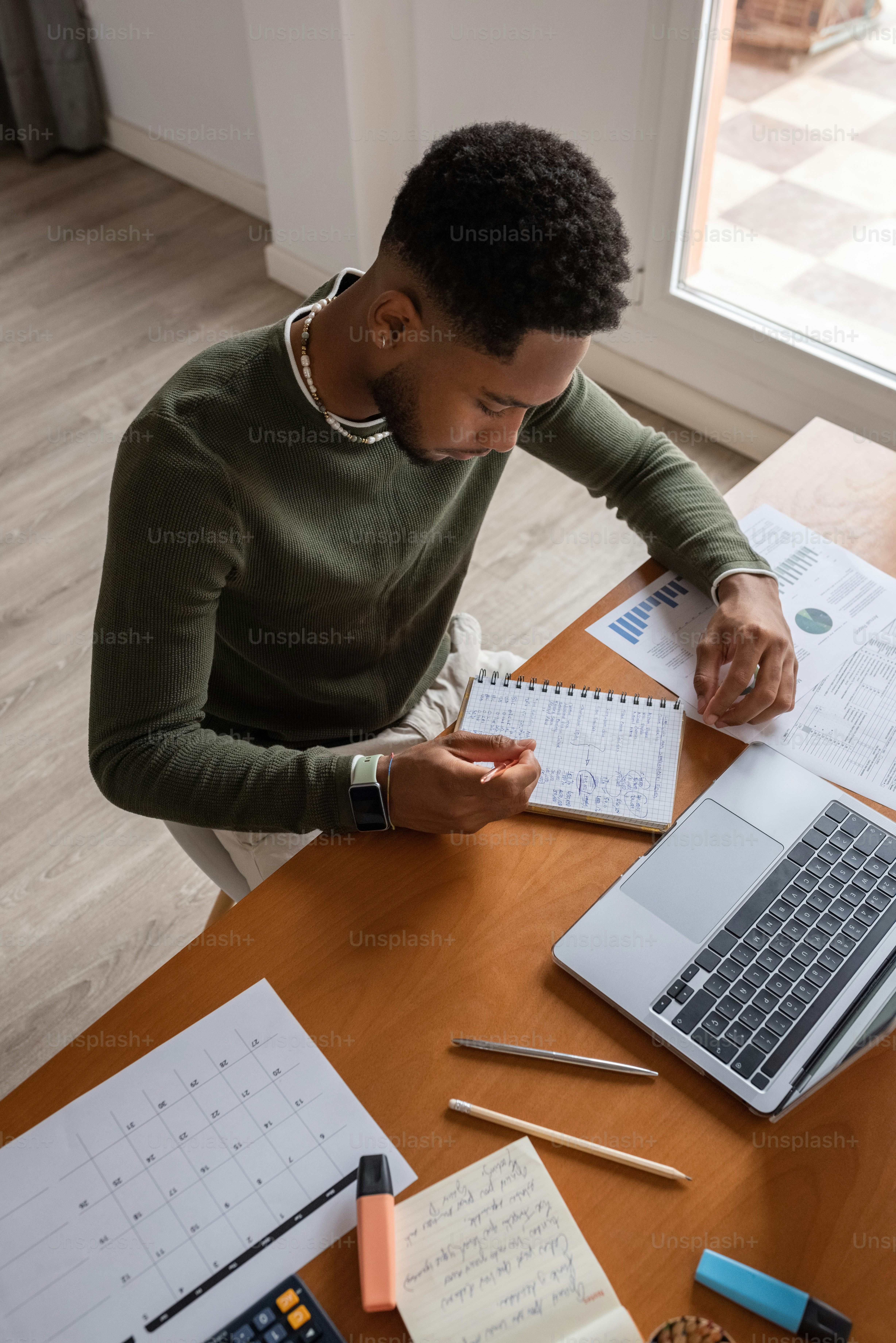 um homem sentado em uma mesa com um laptop e notebook