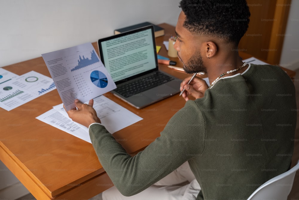 a man sitting at a desk with a laptop and papers