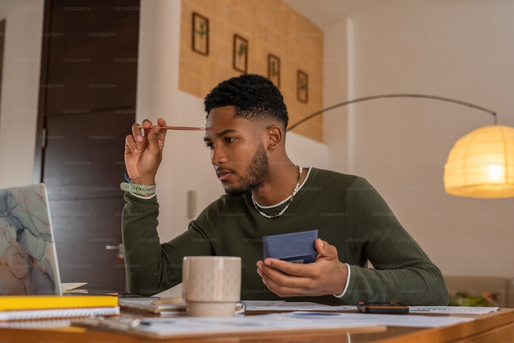 a man sitting at a desk with a laptop and cell phone