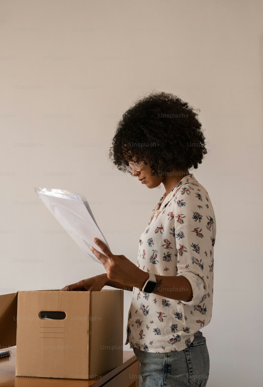 a woman standing in front of a box holding a piece of paper