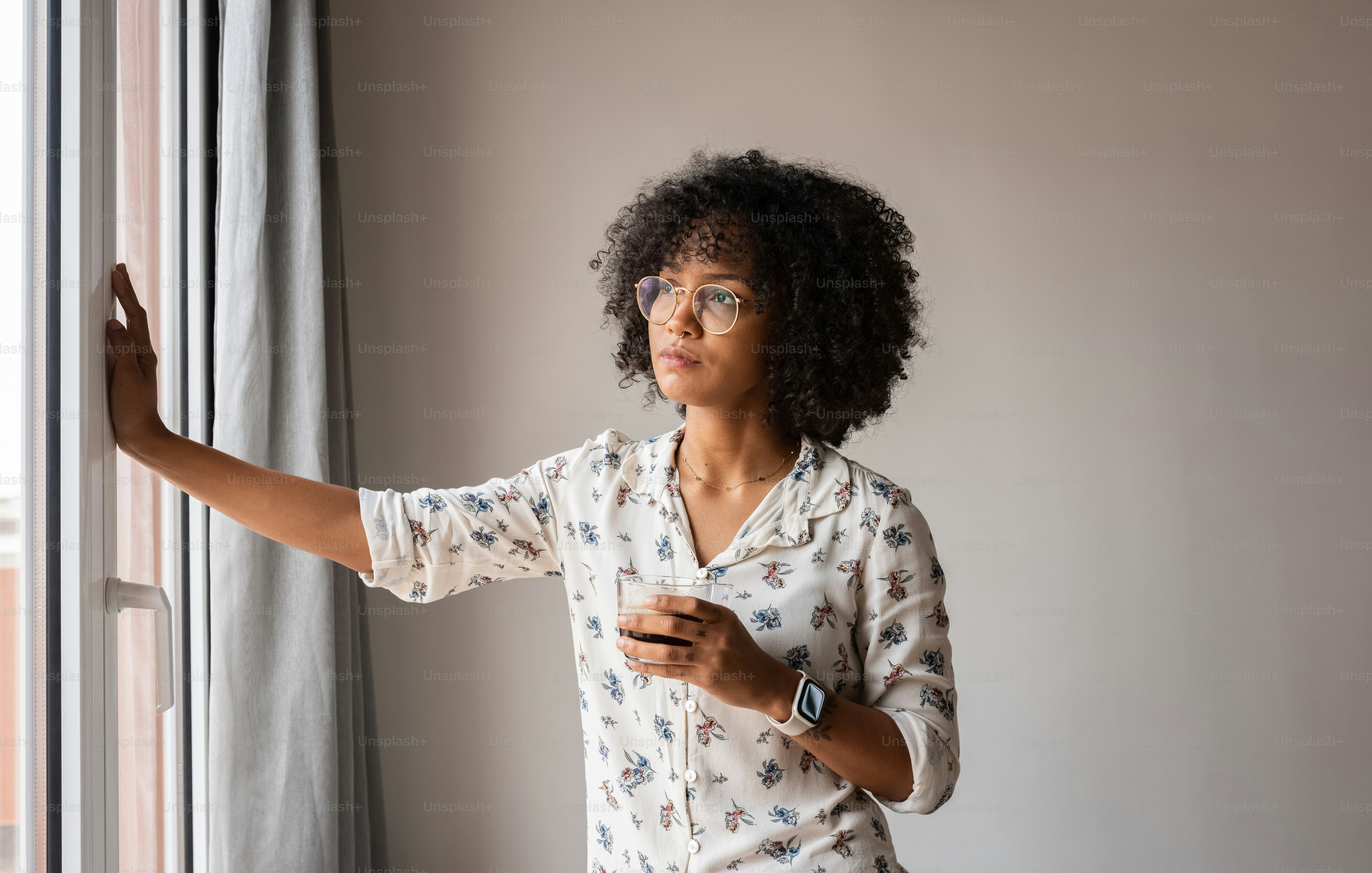 a woman standing in front of a window holding a cell phone