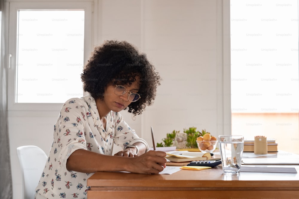 a woman sitting at a desk writing on a piece of paper