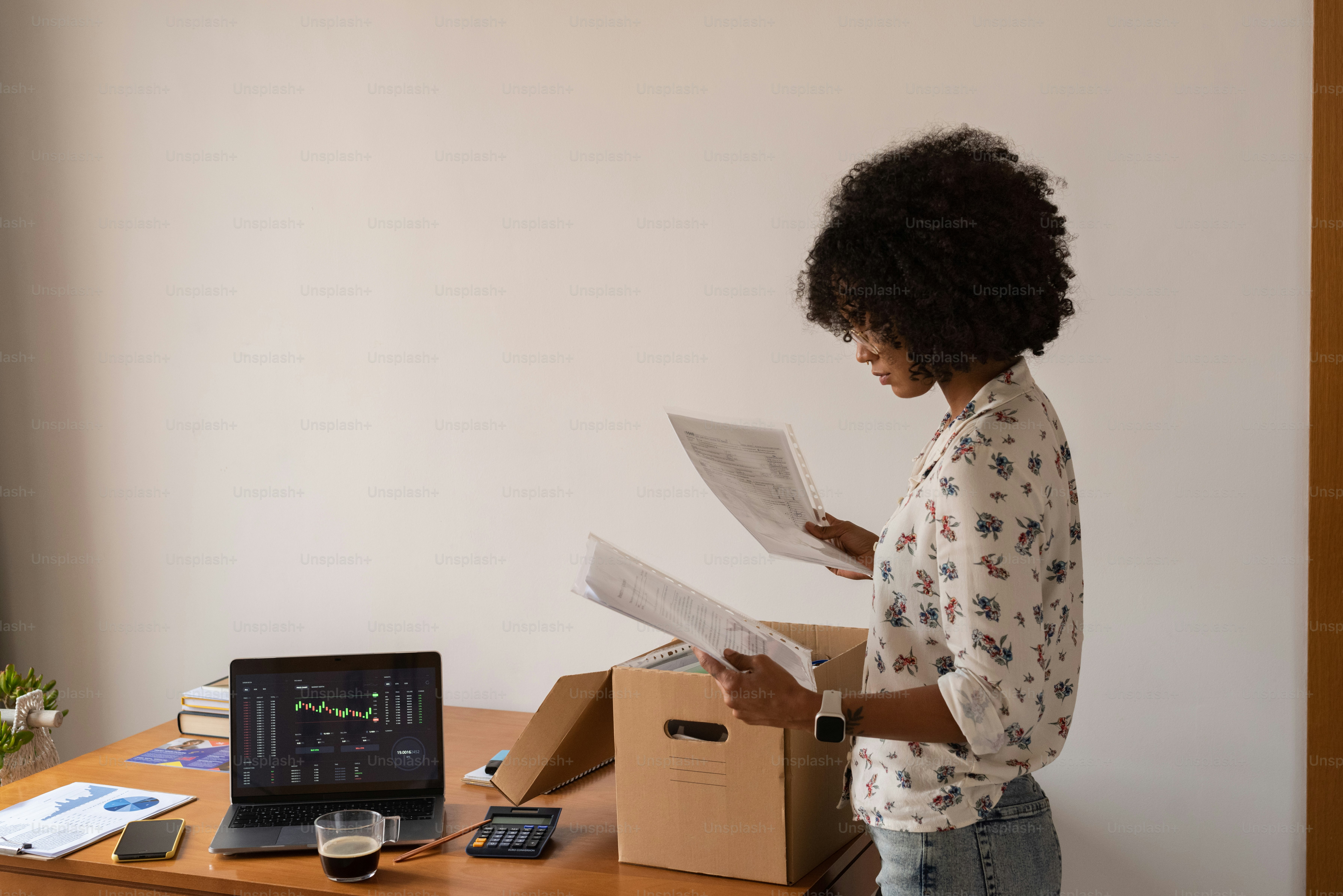 a woman standing in front of a desk reading a paper