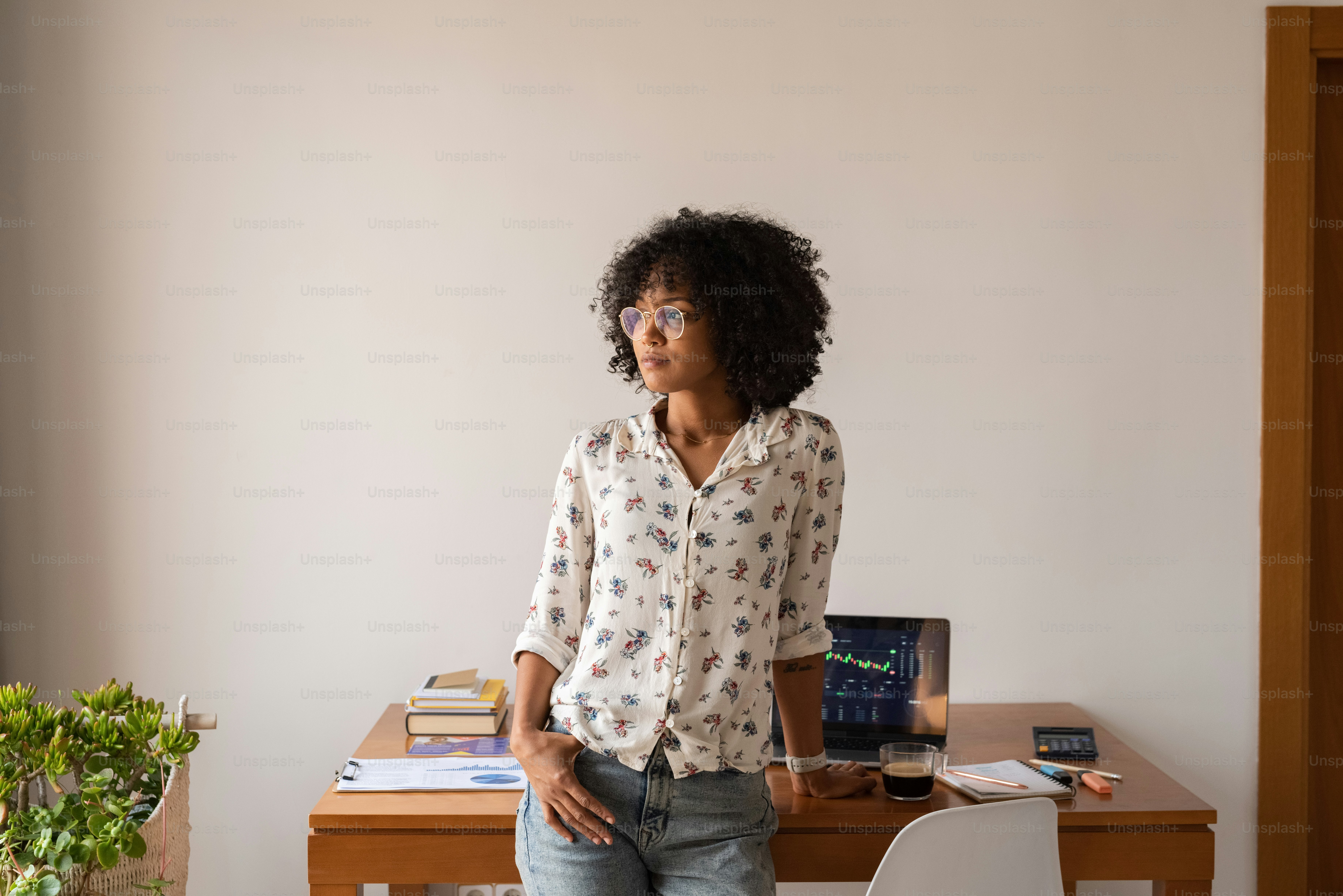 a woman standing in front of a desk with a laptop