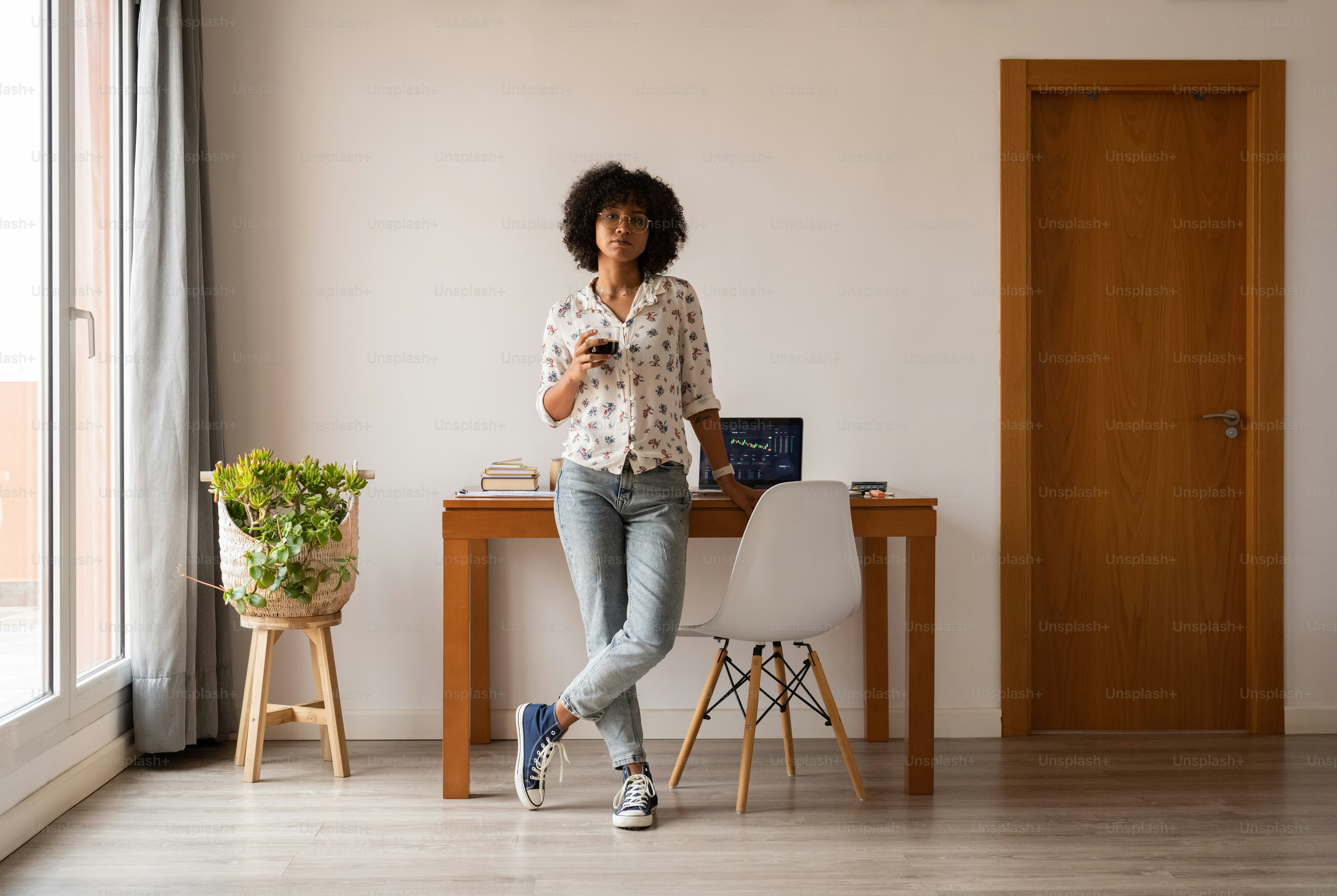 a woman standing in front of a table with a laptop