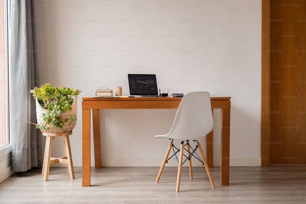 a desk with a laptop and a potted plant