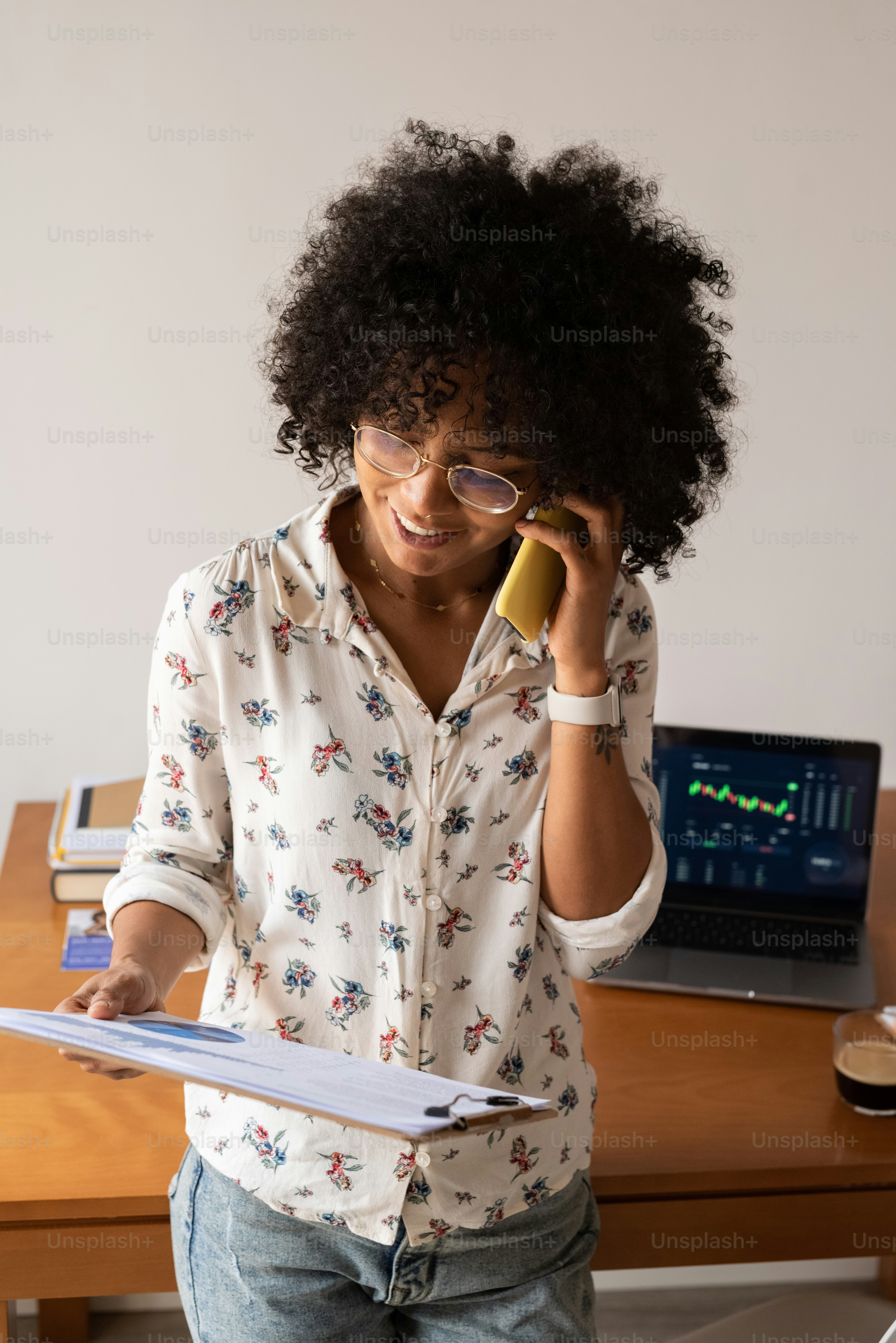 a woman talking on a cell phone while holding a clipboard