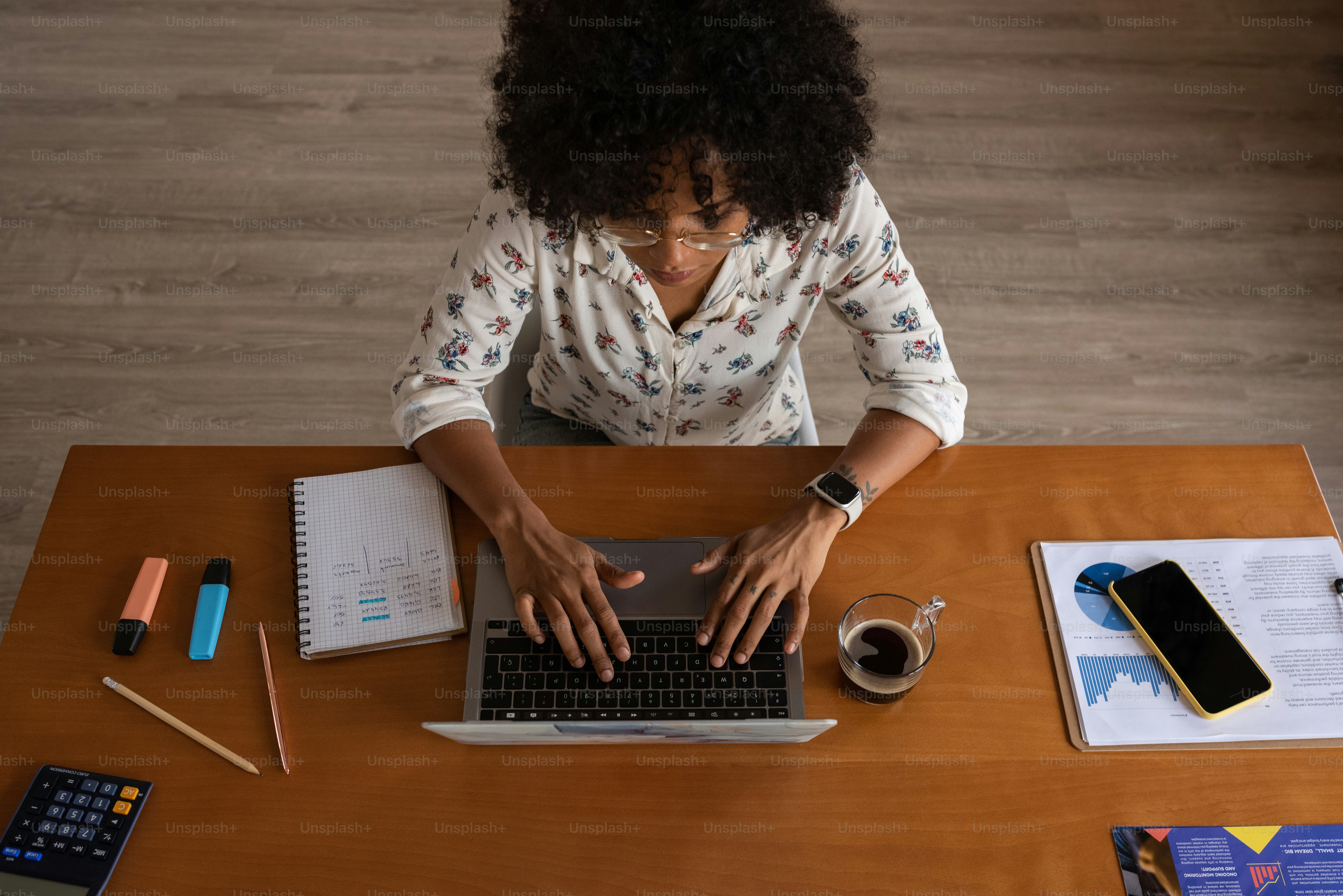 seorang wanita duduk di meja mengetik di laptop