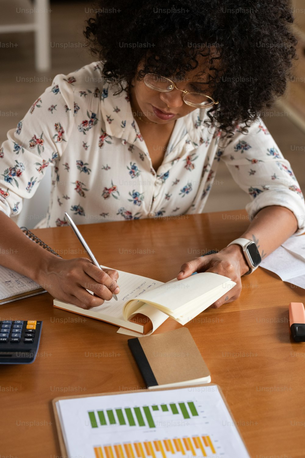 Una mujer sentada en una mesa con un libro y una calculadora