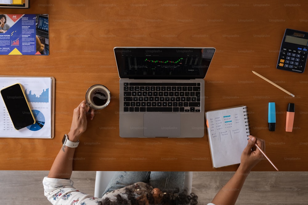 uma pessoa sentada em uma mesa com um laptop e uma xícara de café