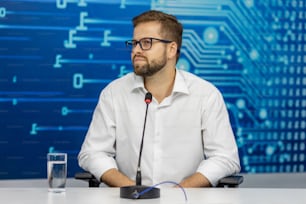 a man sitting at a table with a microphone in front of him