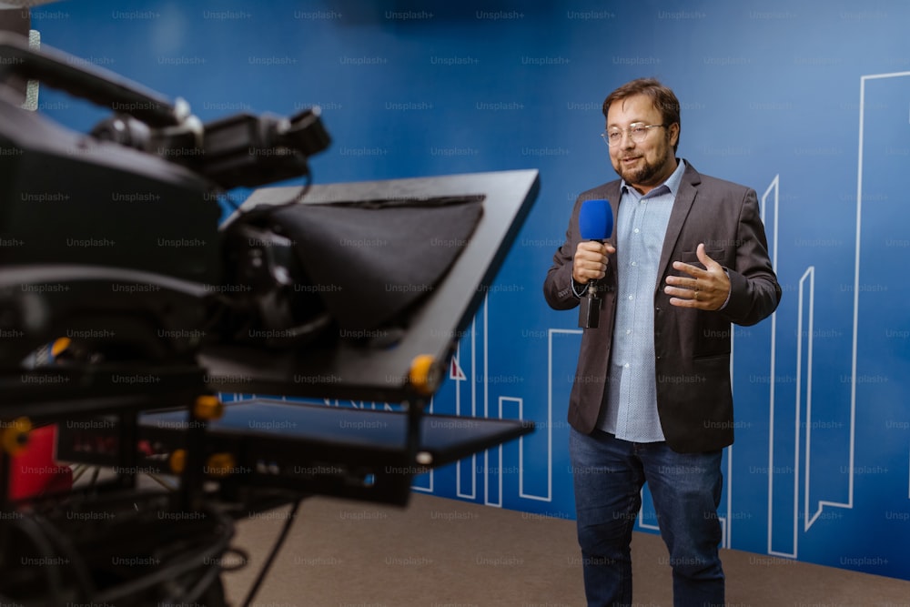 a man standing in front of a camera holding a microphone