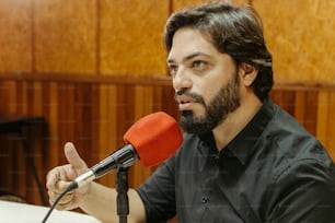 a man with a beard sitting in front of a microphone