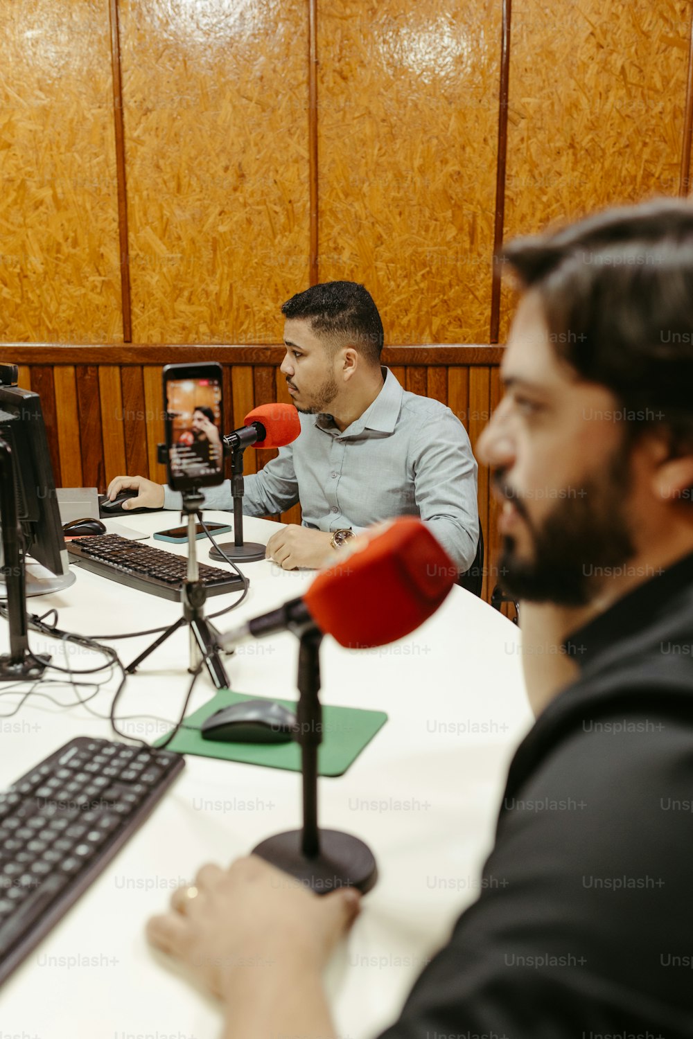 two men sitting at a table with microphones in front of them