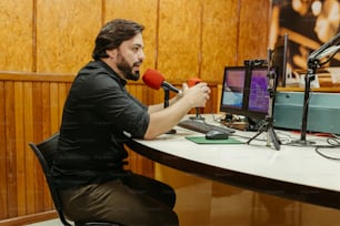 a man sitting at a desk with a microphone
