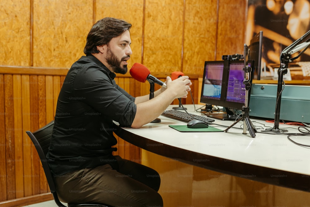 a man sitting at a desk with a microphone