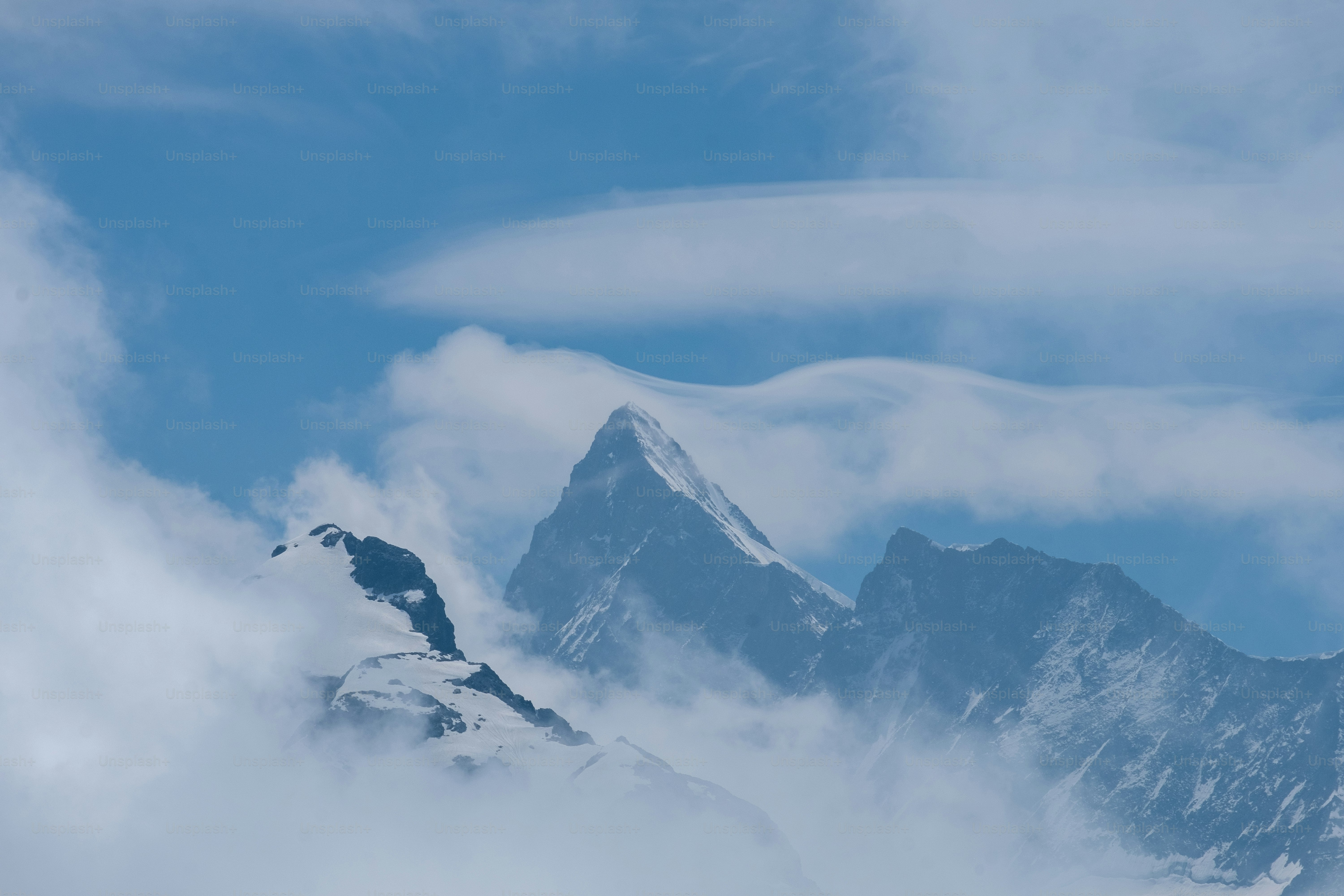 a very tall mountain covered in clouds under a blue sky