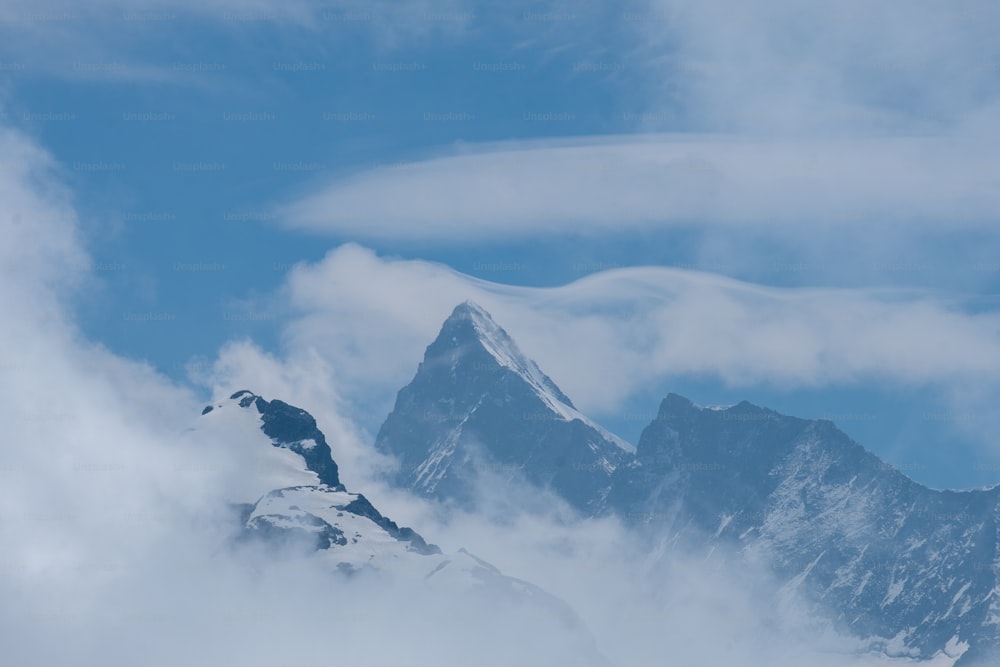 uma montanha muito alta coberta de nuvens sob um céu azul