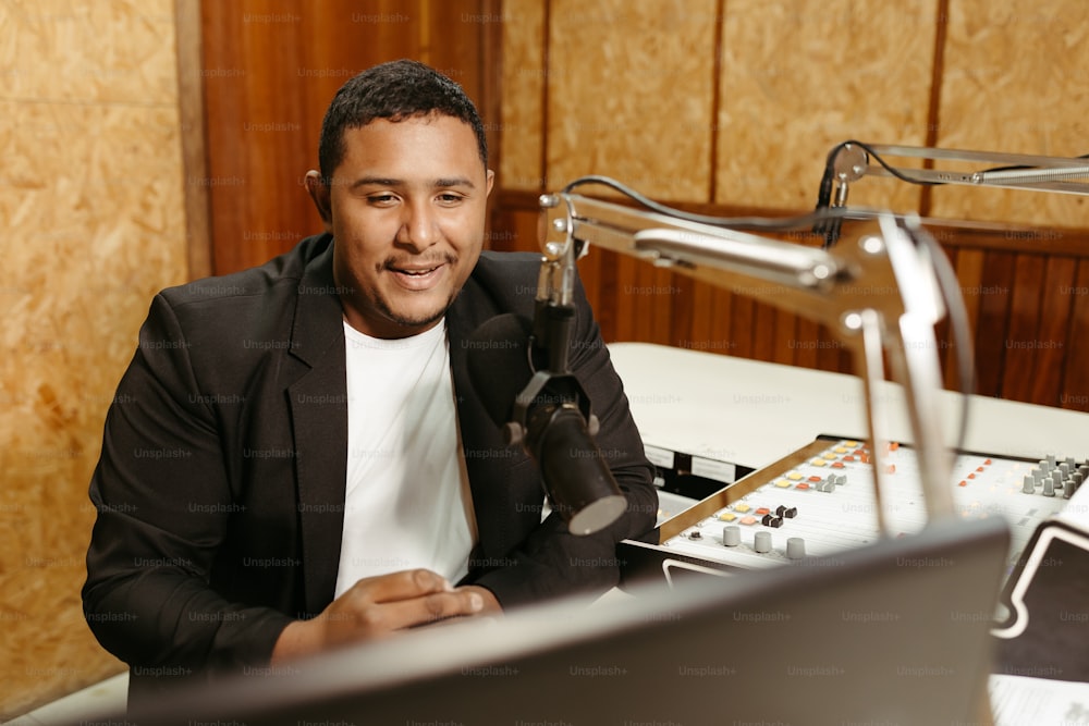 a man sitting in front of a microphone in a recording studio