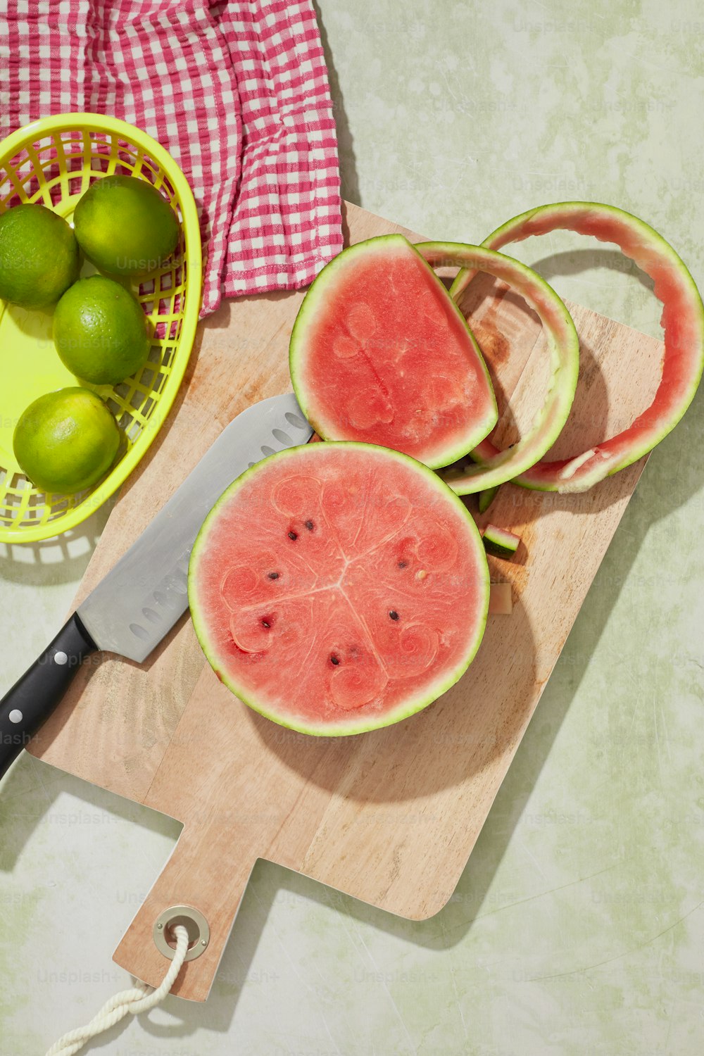 uma tábua de corte com fatias de melancia e uma faca