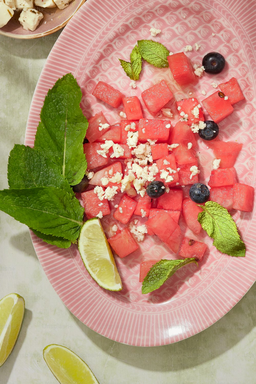 a plate of watermelon, mint, and feta cheese salad