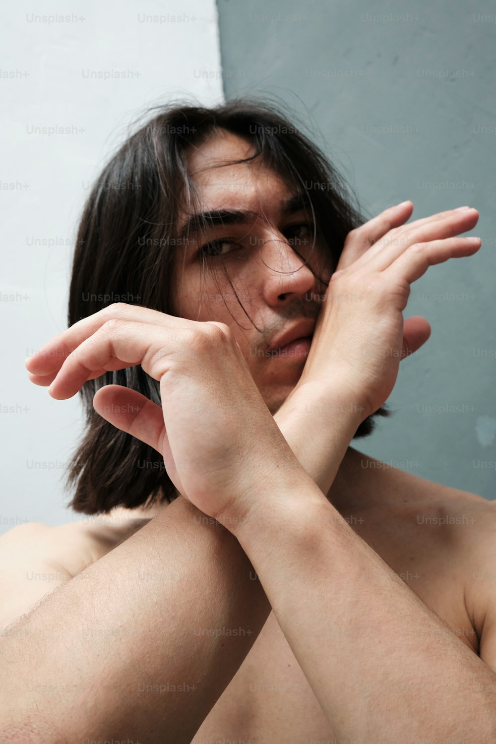 a shirtless man holding his hands to his face