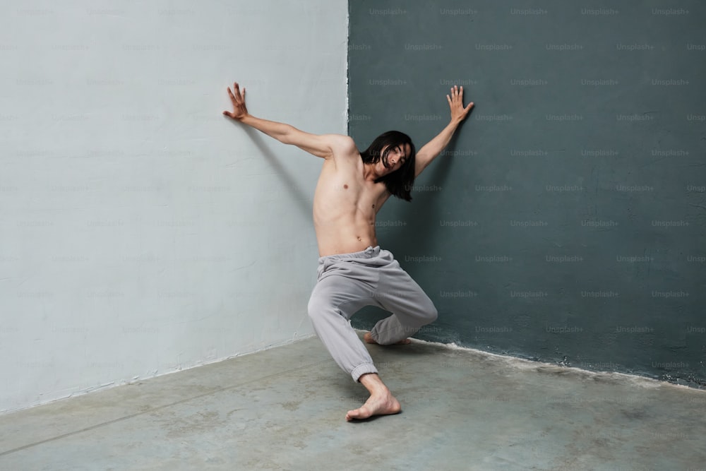 a shirtless man leaning against a wall