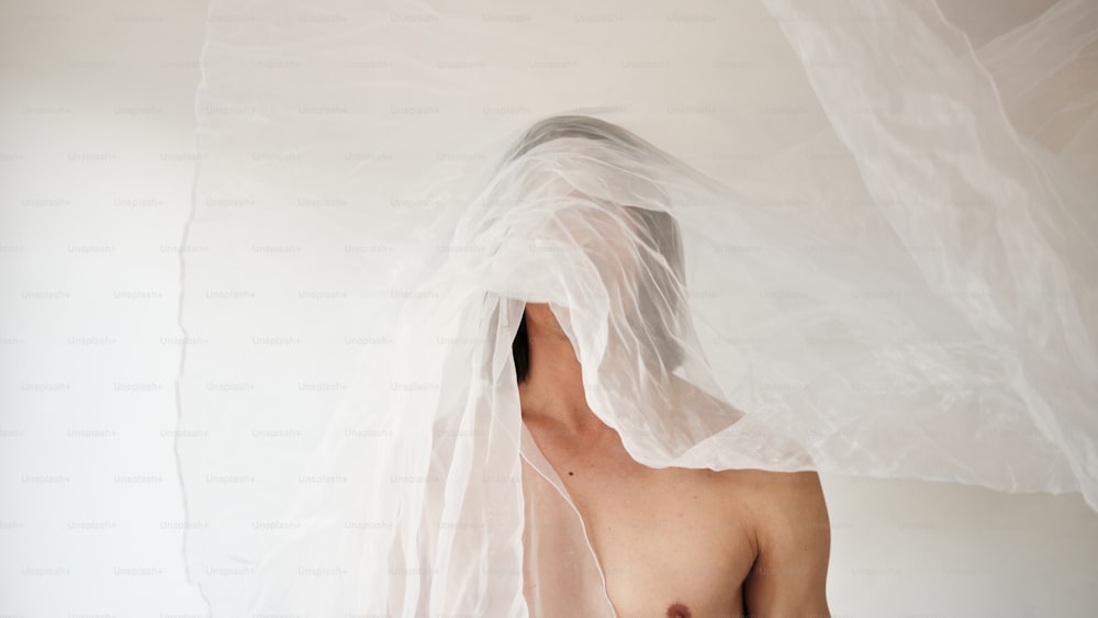 a shirtless man with a white veil over his head