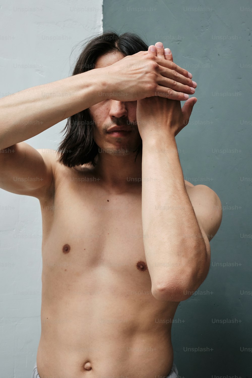 un uomo a torso nudo che si tiene le mani sul viso