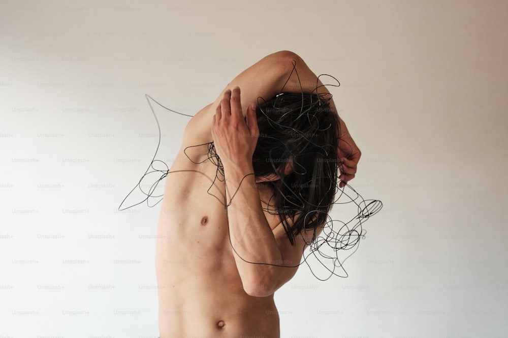 a shirtless man holding his head in his hands