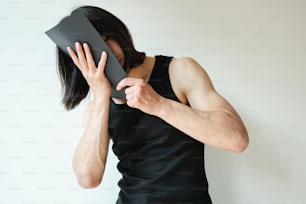 a woman covering her face with a black piece of paper