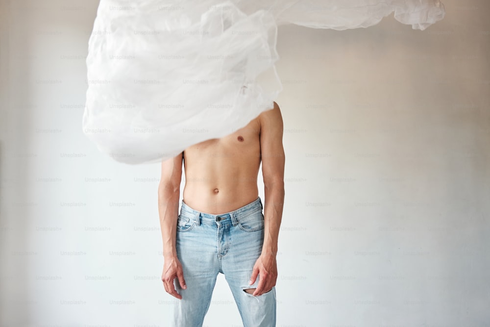 a shirtless man standing in front of a white sheet