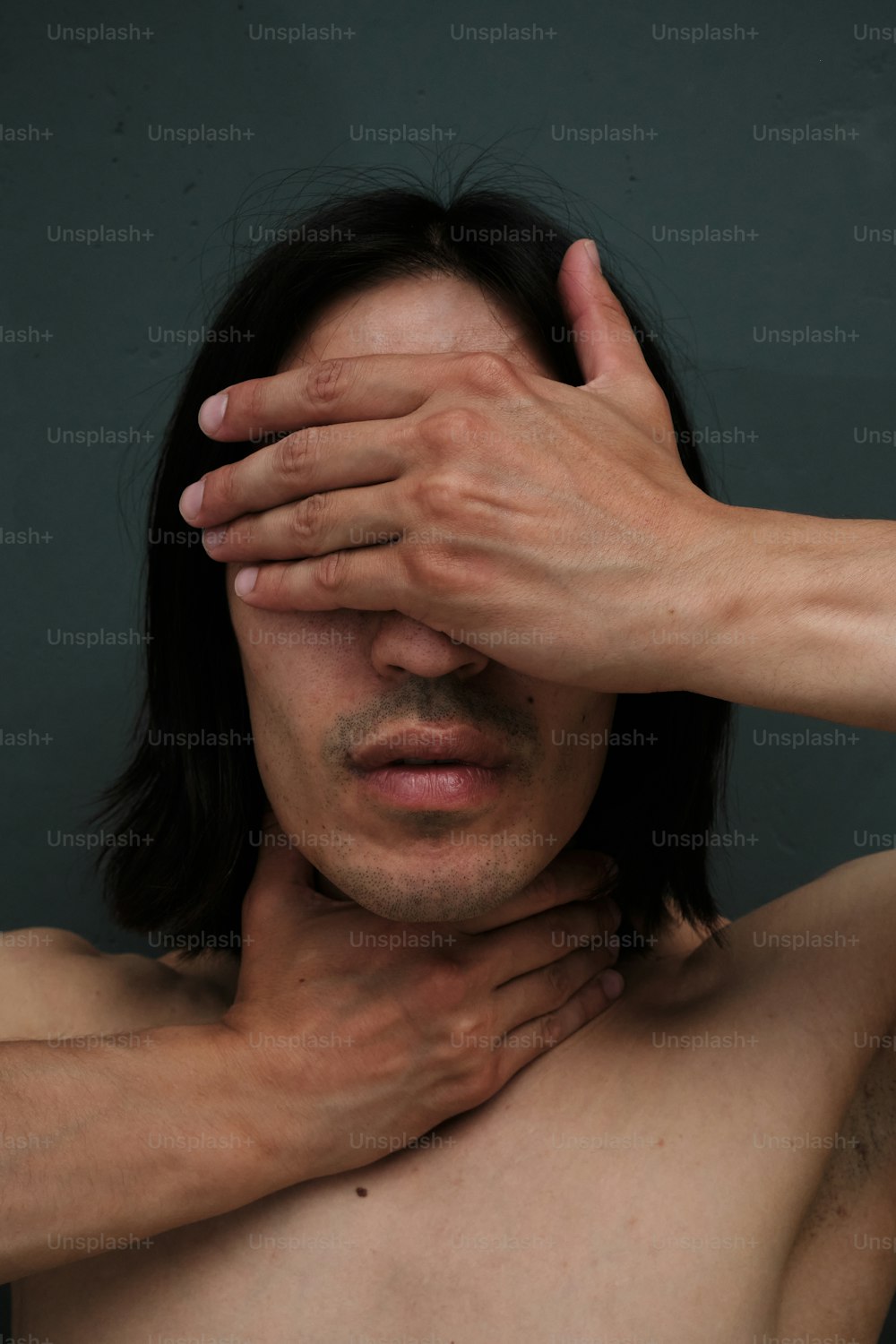 a shirtless man holding his hands to his face