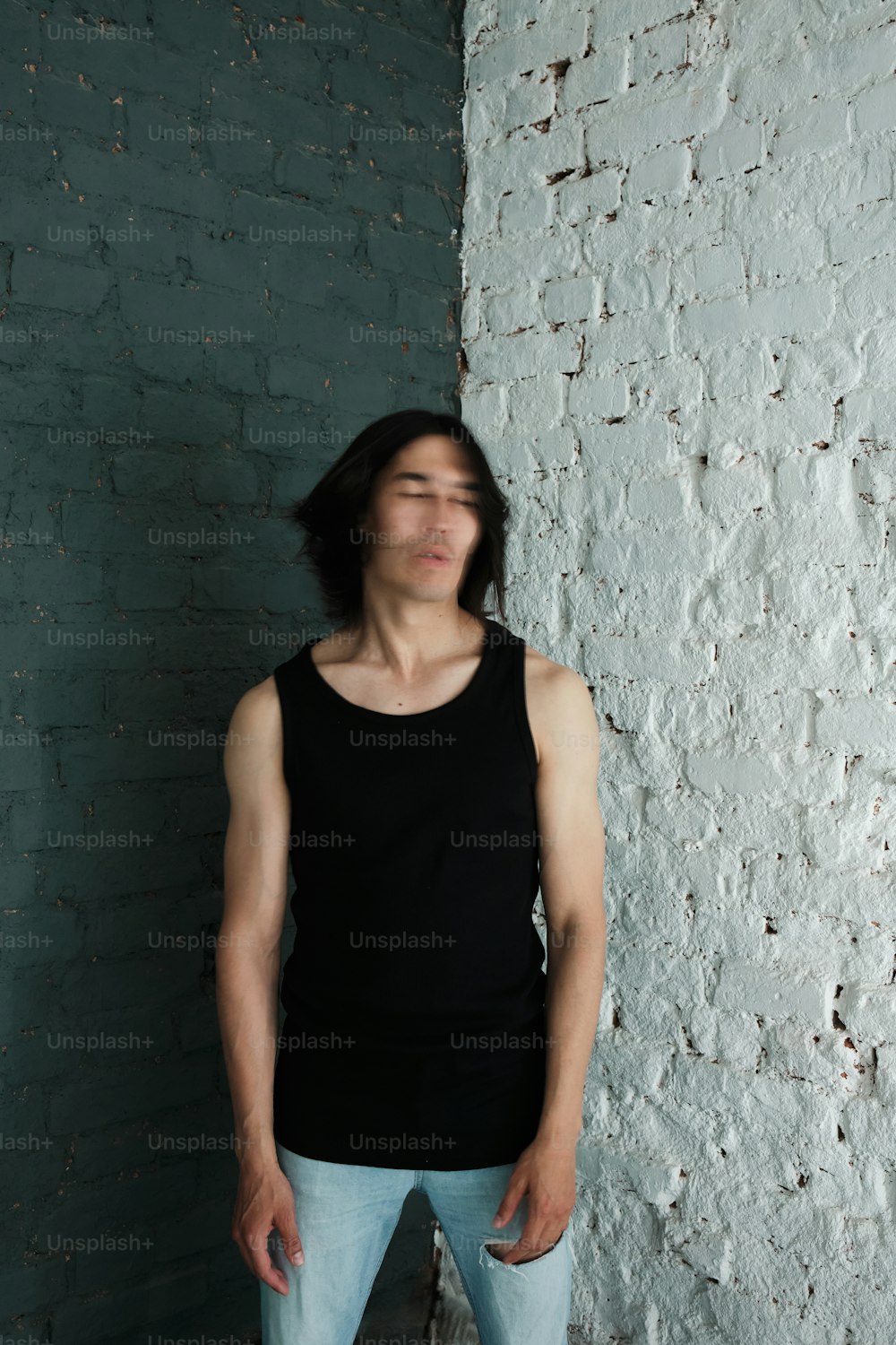 a man standing in front of a white brick wall